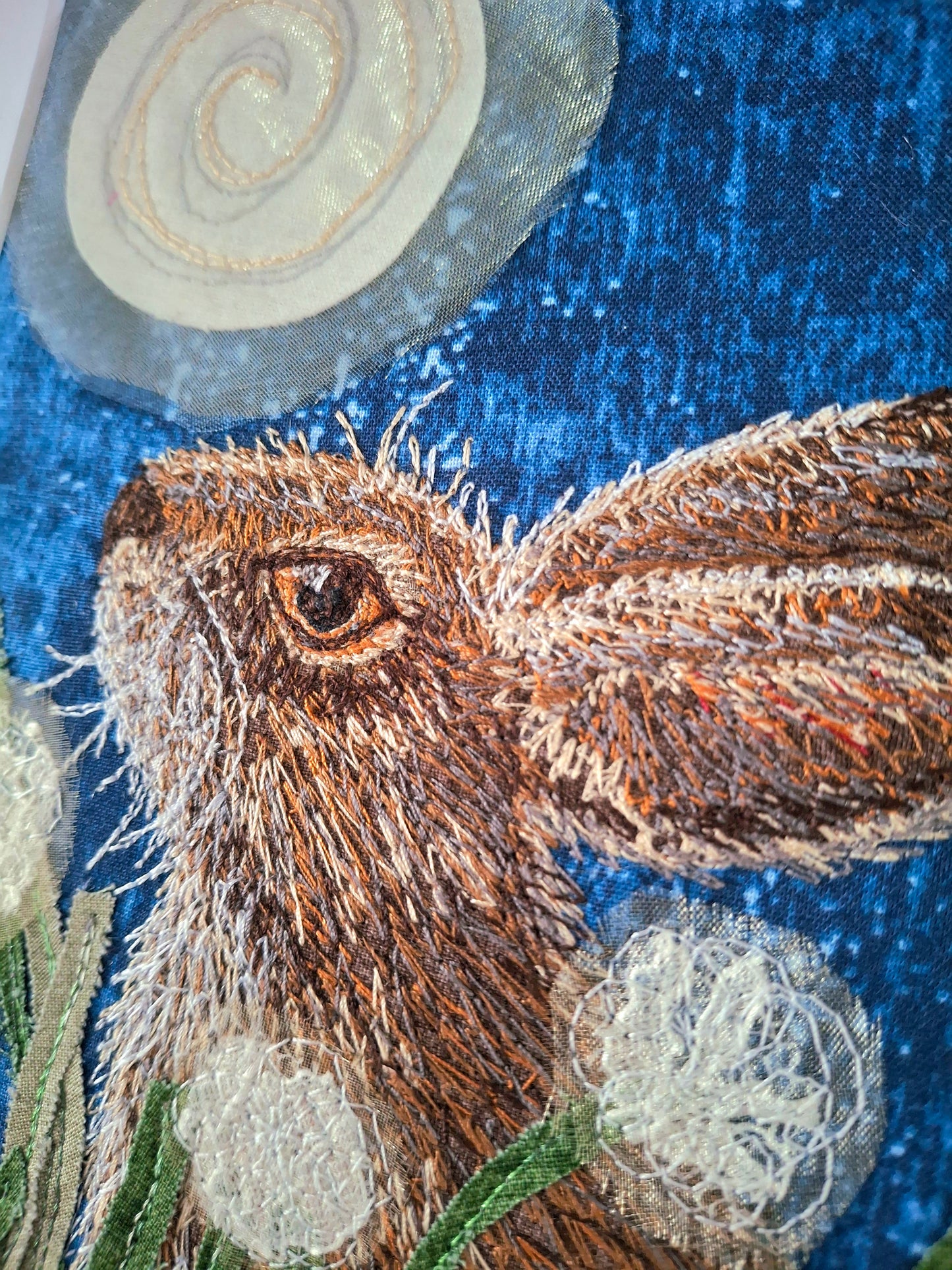 Embroidered design of a hare with a textured blue background