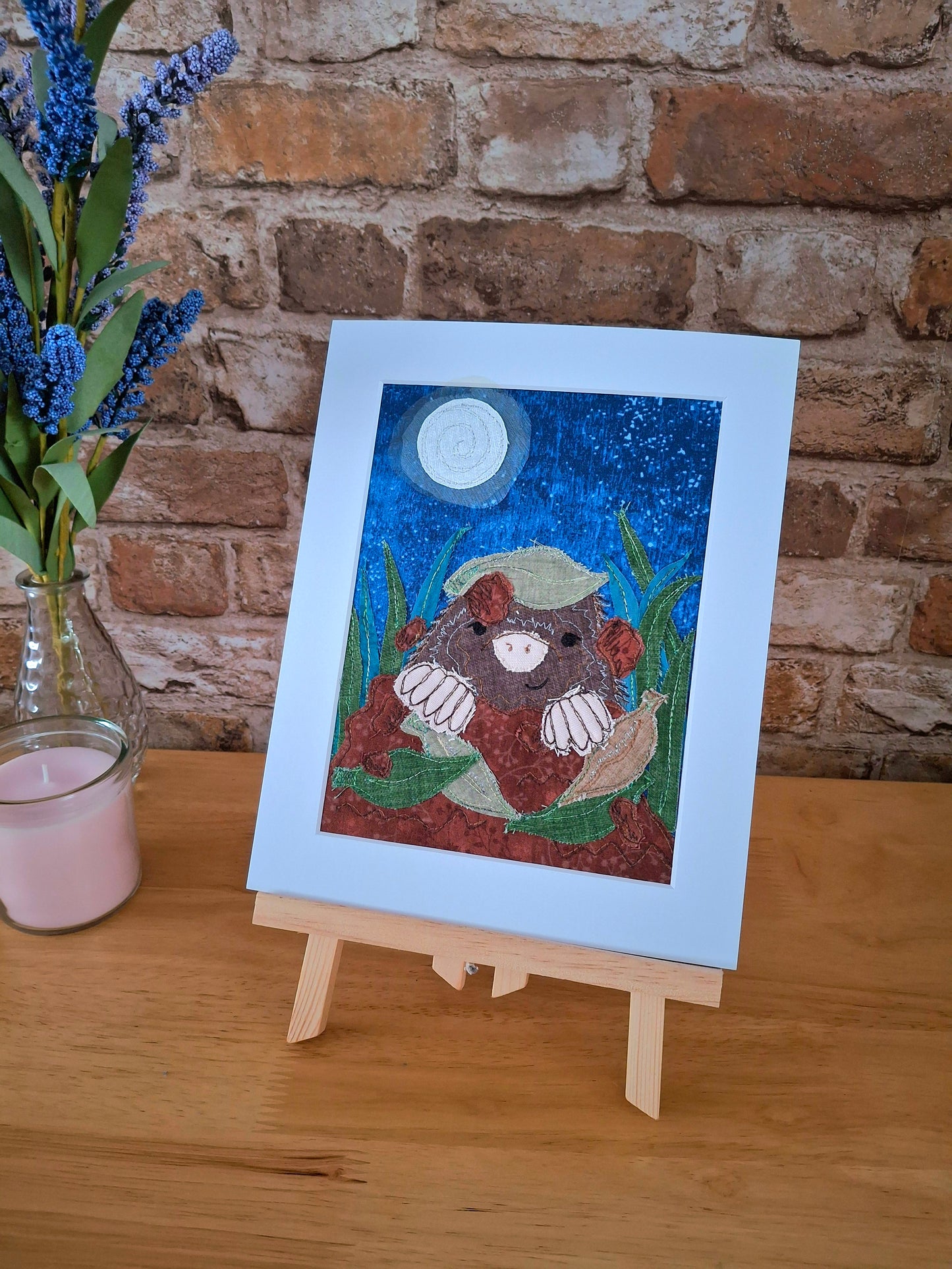 Mounted artwork of a mole with a moonlit sky on a wooden surface with a brick wall background.