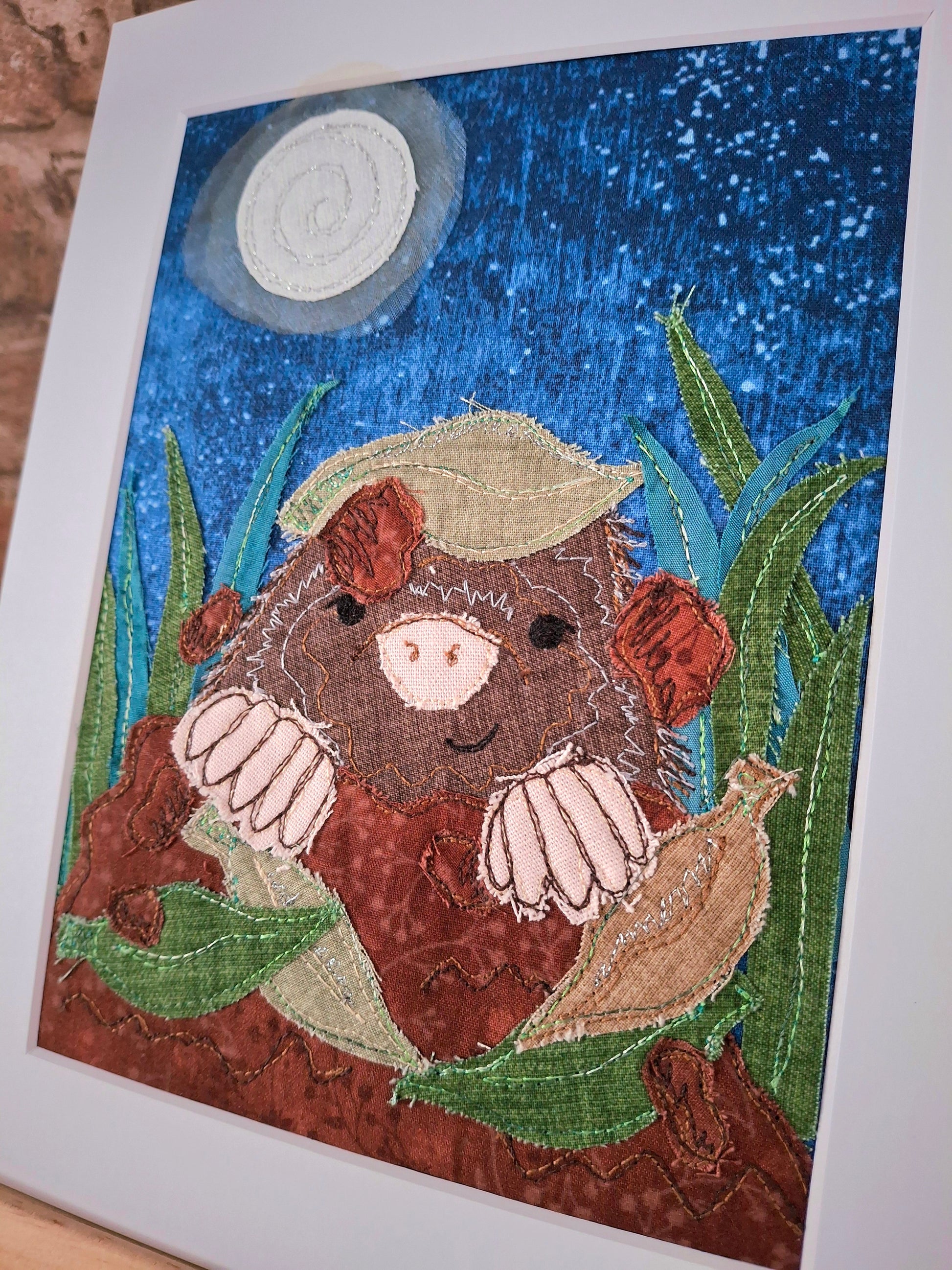 Textile Artwork of a mole coming out of the ground with a night sky and moon background