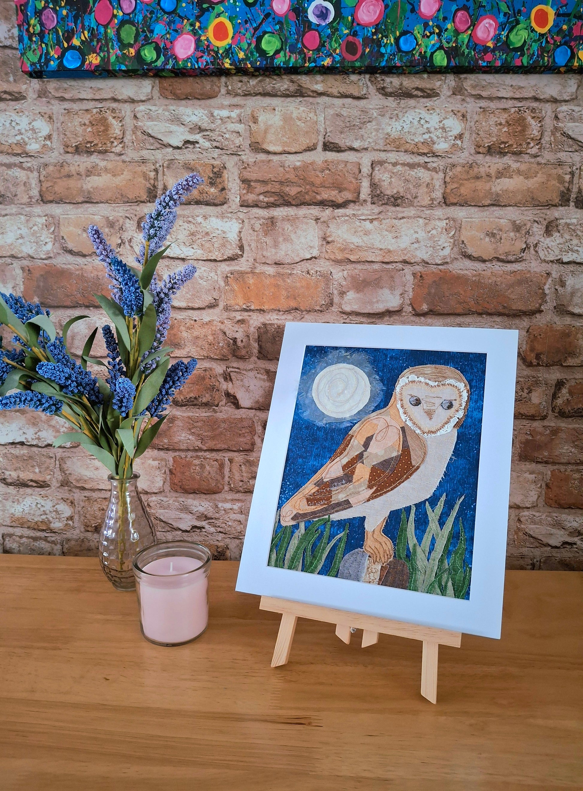 Mounted artwork of a owl on a wooden table with a brick wall background