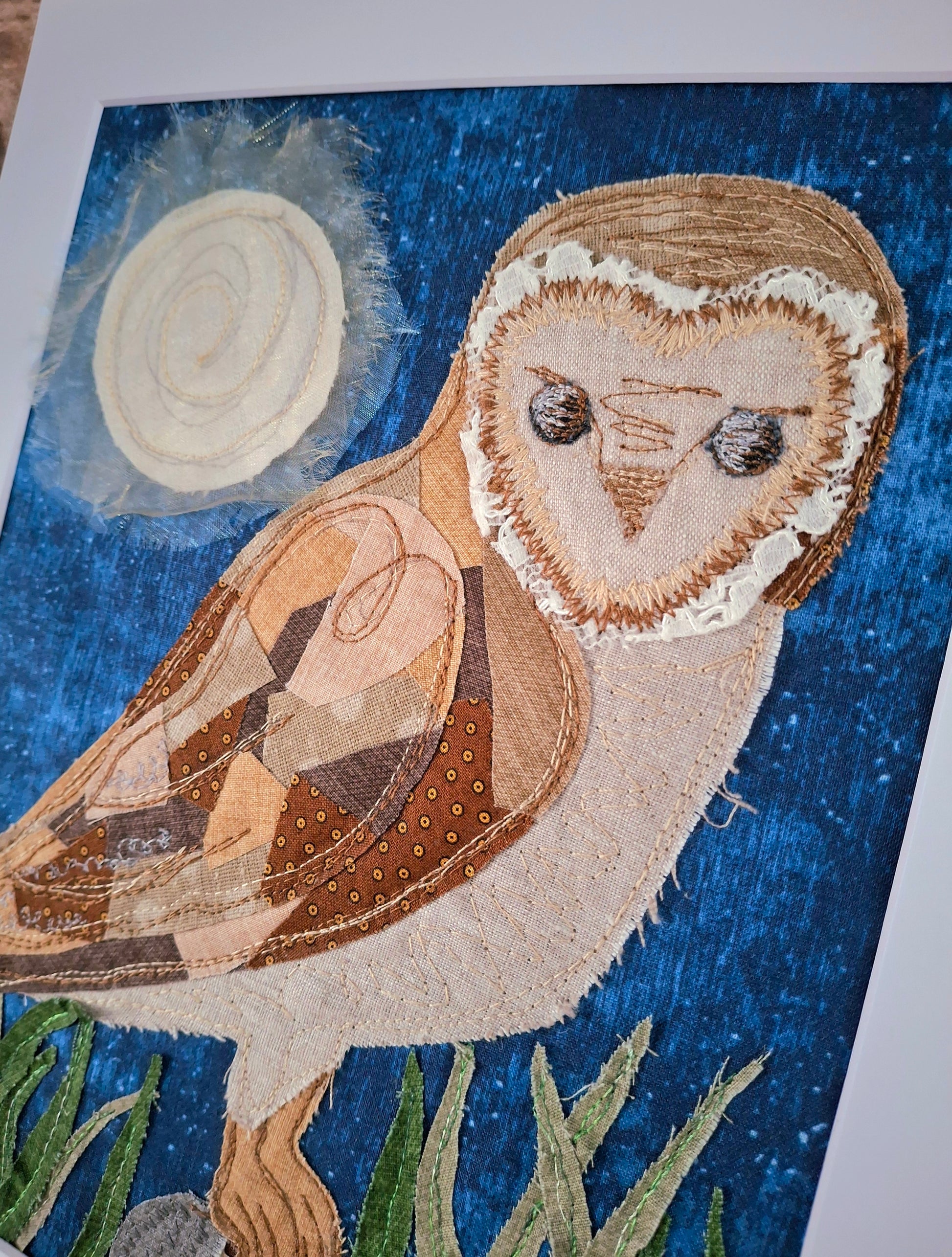 Textile art of an owl with a blue background